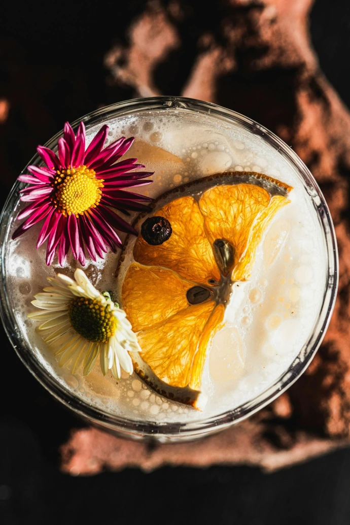 Cocktail garnished with orange slice and flowers